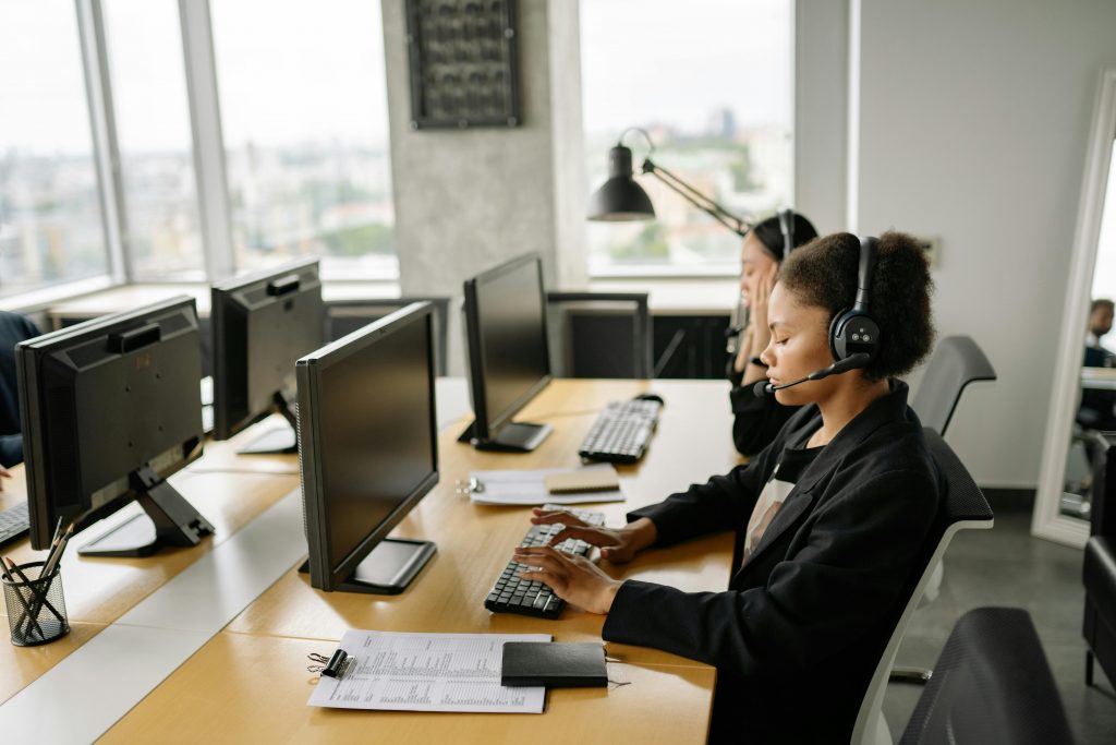 Customer support agents working at a call center with computers and headsets, focusing on tasks.